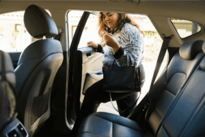 A young woman gets into the backseat of a rideshare vehicle